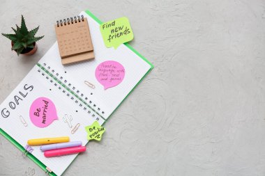 Yapılacaklar listesi boş olan defter, gri arkaplanda yapışkan notlar ve kırtasiye malzemesi. Yeni yıl hedefleri kavramı