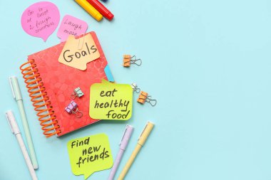 Planlar, defter ve kırtasiye malzemeleriyle birlikte mavi arka planda yapışkan notlar. Yeni yıl hedefleri kavramı