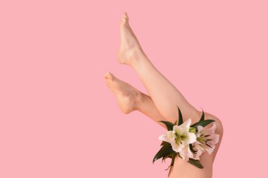 Pembe arka planda güzel beyaz zambak çiçekleri olan genç bir kadının bacakları.