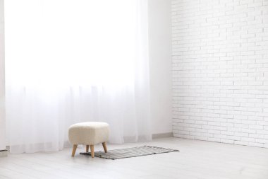 Pouf, halı ve ışık perdeleri beyaz odada.