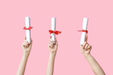 Pembe arka planda kurdeleli kadın diploması.