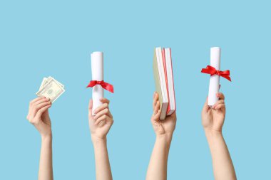 Diplomalı kadın elleri, para ve mavi arkaplan üzerine not defterleri