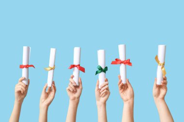 Mavi arka planda diploması olan kadın eller