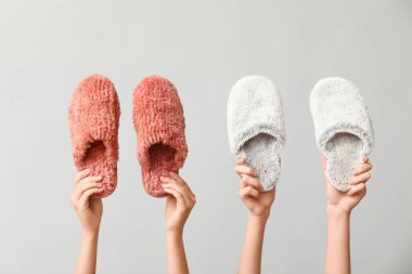 Beyaz arka planda terlikleri tutan kadın eller.