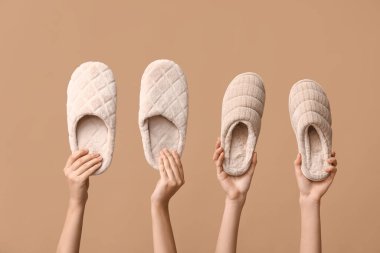 Bej arka planda terlikleri tutan kadın eller.