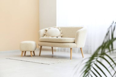 Oturma odasının iç tarafında halı ve ışık perdesi olan rahat bir kanepe.