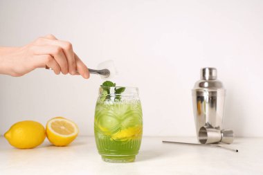 Lezzetli limonata, limon ve nane şekerli beyaz arka planda kadın eli.