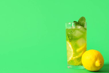 Yeşil arka planda limonlu ve naneli bir bardak lezzetli limonata.
