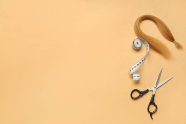 Bağış için kırmızı saç teli, makas ve turuncu arka planda mezura.