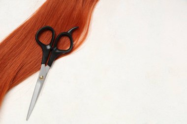 Kırmızı saç teli, beyaz arka planda makasla bağış için.