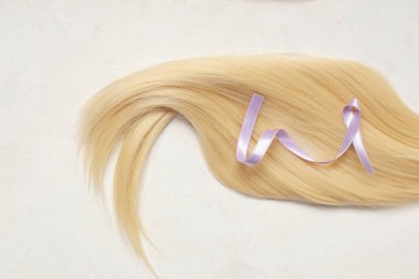 Bağış için sarı saç teli ve beyaz arka planda mor farkındalık kurdelesi.