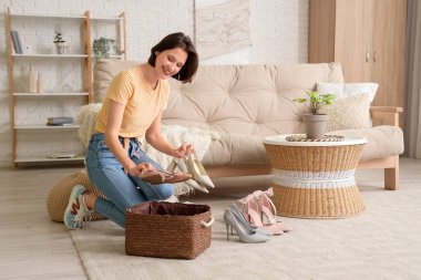 Genç bir kadın evde farklı topuklu ayakkabılar giyiyor.