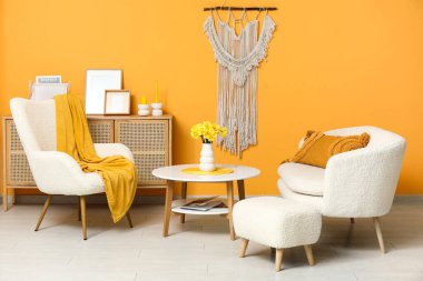 Beyaz koltuklu, yastıklı ve kahve masalı güzel bir oturma odası.