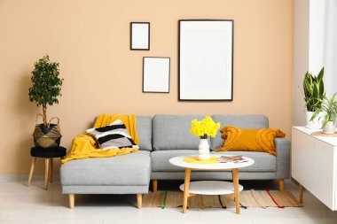 Oturma odasında rahat bir kanepe, sehpa ve vazo çiçekleri var.