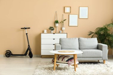 Oturma odasındaki beyaz çekmecelerin yanında elektrikli scooter.