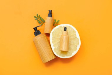 Kozmetik ürünler, yapraklar ve turuncu arka planda taze zeytinyağı.