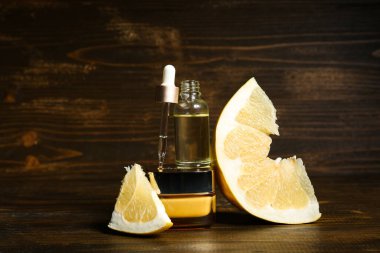 Şişe, kozmetik ürünleri kavanozu ve ahşap arka planda bir parça pomelo, yakın plan.