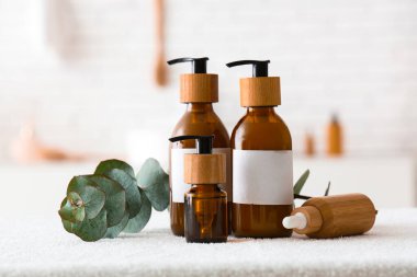 Kozmetik ürünler ve okaliptüs dalları banyodaki masada, yakın plan.