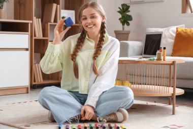 Genç bir kadın odada tek kullanımlık farklı sigaralarla yerde oturuyor.