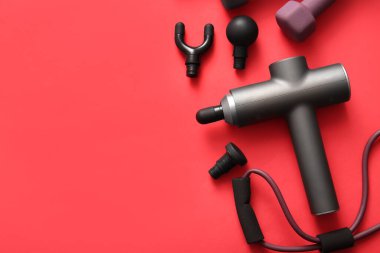 Kırmızı arka planda vurmalı masaj aleti ve spor ekipmanı olan kompozisyon