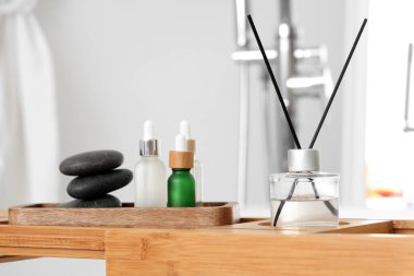 Ahşap tepside aroma yayıcı ve banyoda gerekli yağ şişeleri, yakın plan.