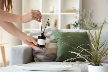 Evde koku yayıcı tutan kadın.