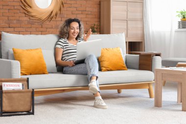 Evinde dizüstü bilgisayarı ve parmağı kırmızı iple gezen orta yaşlı güzel bir kadın. Hatırlatma konsepti