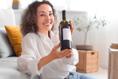 Evde bir şişe şarabı olan orta yaşlı güzel bir kadın.