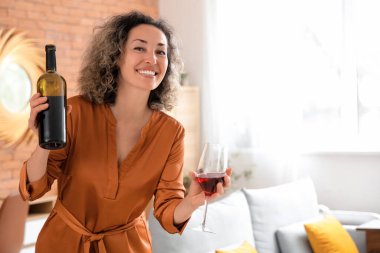 Evinde şişe ve bir bardak kırmızı şarapla orta yaşlı güzel bir kadın.