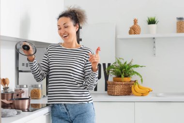 Mutfakta yemek pişirirken parmağında kırmızı ip olan orta yaşlı bir kadın. Hatırlatma konsepti