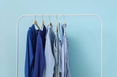 Mavi duvarın yanında kadın kıyafetleriyle dizilin.