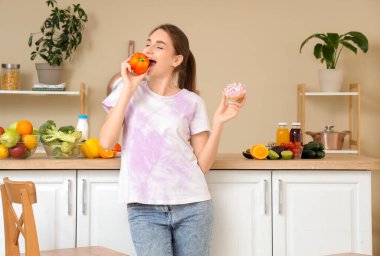 Donutlu genç bir kadın mutfakta dolmalık biber yiyor. Diyet kavramı