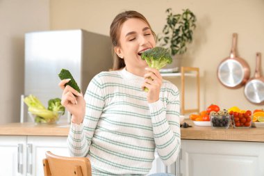 Mutfakta salatalıklı brokoli yiyen genç bir kadın. Diyet kavramı