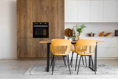 Mutfağın içinde yemek masası ve beyaz tezgahlar var.