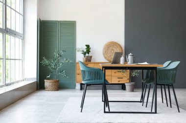 Yemek masası, katlanan ekran ve çekmeceleri olan şık bir oda.