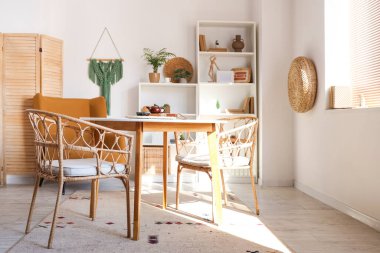 Yemek masası, koltuk ve raf üniteleri olan ışık odasının içinde.