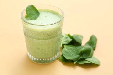 Sarı arka planda bir bardak taze ıspanaklı smoothie.