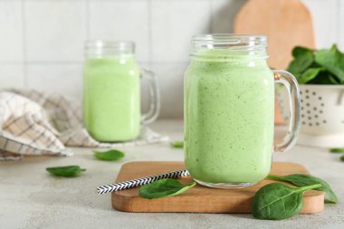 Mason jars of fresh spinach smoothie on white table