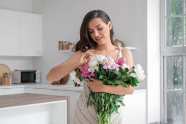 Mutfakta şakayık çiçekleri olan güzel bir kadın.