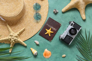 Yeşil grunge arka planda deniz yıldızları, şapka, pasaport ve fotoğraf makinesiyle güzel bir kompozisyon