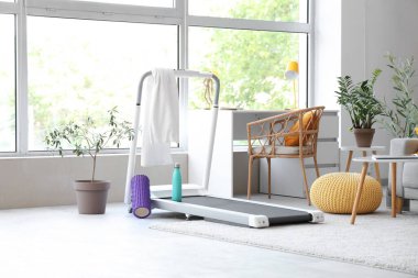 Oturma odasında havlu, su şişesi ve köpük sarmalı koşu bandı.