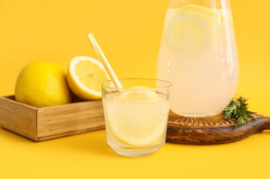 Sarı arka planda biberiyeli bir bardak taze limonata.