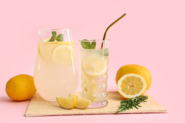 Bir bardak taze limonata ve pembe arka planda nane şekeri.