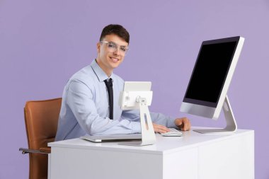 Genç işadamı masadaki bilgisayarla leylak arkaplanı üzerinde çalışıyor.