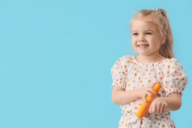 Mavi arka planda güneş kremi süren tatlı küçük kız.