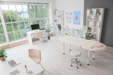 Çalışma yerleri, masaj koltuğu ve raf üniteleri olan bir hastane.