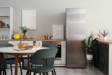 Buzdolabı, tezgah ve yemek masası olan modern mutfağın şık iç tasarımı.