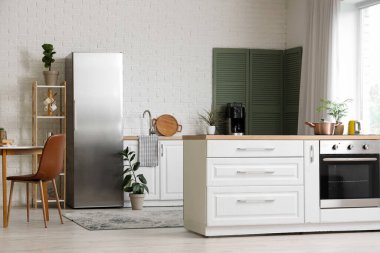 Buzdolabı, yemek masası ve fırınlı tezgahı olan modern stil bir mutfak.