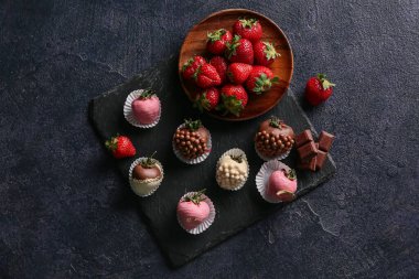 Çikolata kaplı çilek ve siyah arka planda taze böğürtlen tabağı.