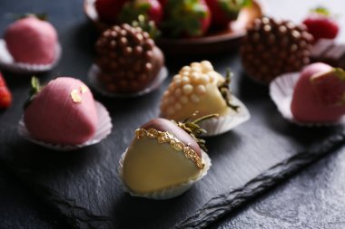 Siyah arka planda çikolata kaplı çilekler, yakın plan.